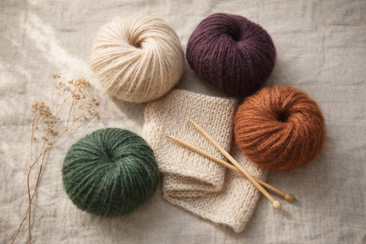 Photo à plat de pelotes de laine et d'aiguilles à tricoter — MOHAIR LUXE, LACE ou ZEN : trois compagnons naturels pour l’hive