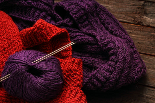 a close up of a ball of yarn and a ball of knitting needles
