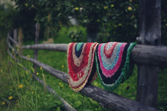 A blanket hanging on a wooden fence in a field