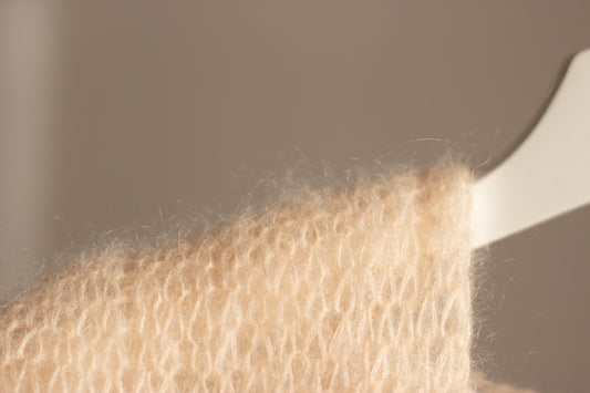 Close-up of a fuzzy, cream-colored knitted fabric.